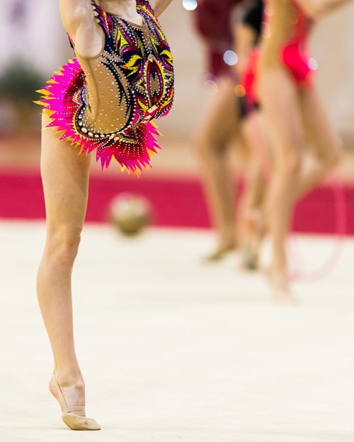 gymnast in bright neon colour patterned competition leotard performing on mat